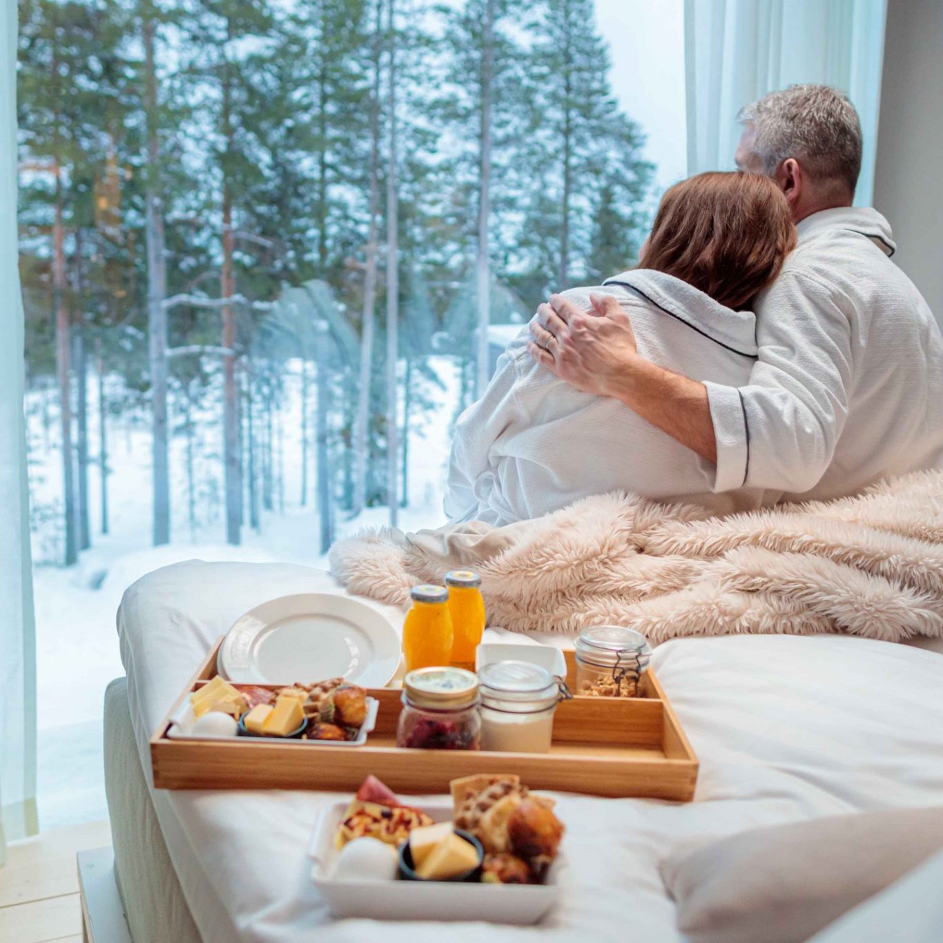 Couple enjoying slow morning and breakfast in bed at Arctic TreeHouse Hotel.