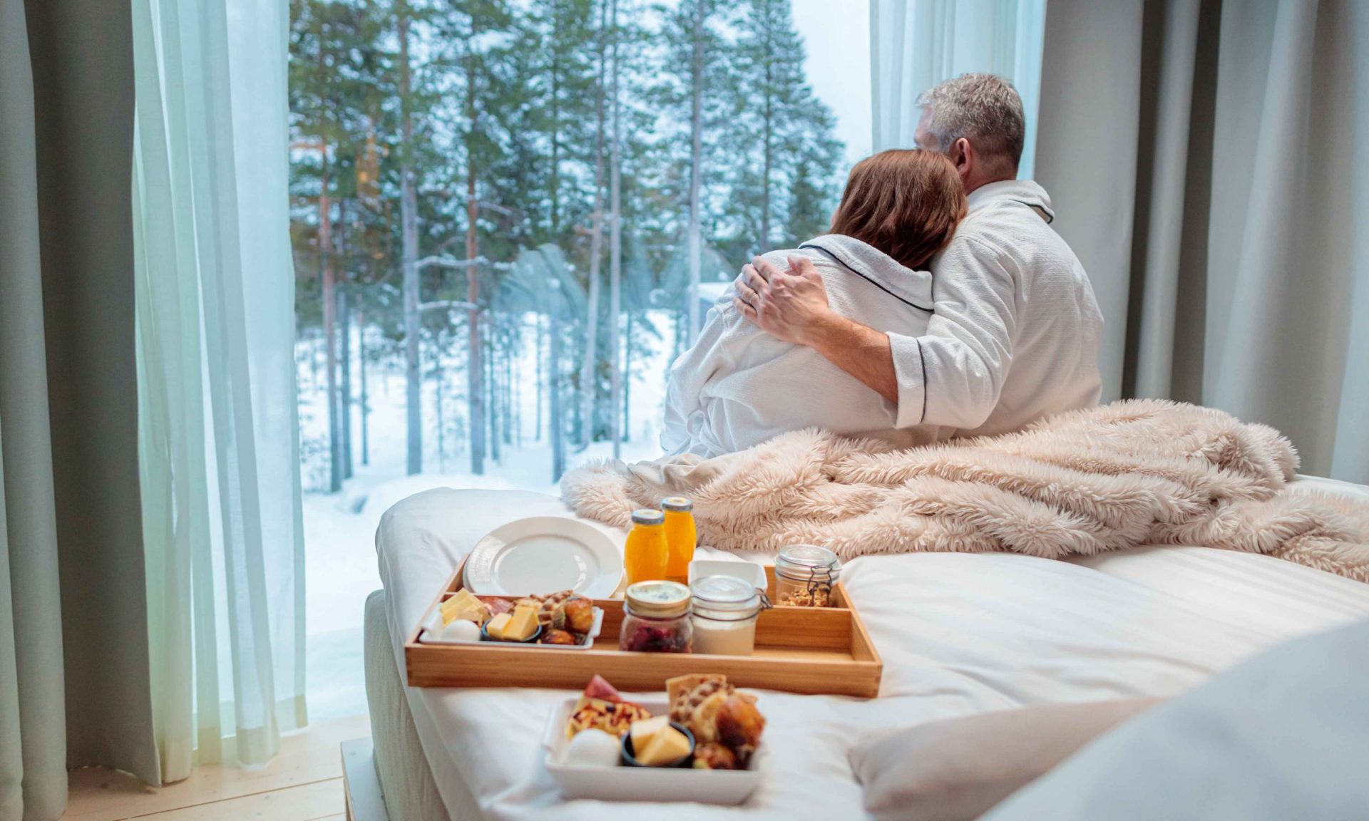 Couple enjoying slow morning and breakfast in bed at Arctic TreeHouse Hotel.