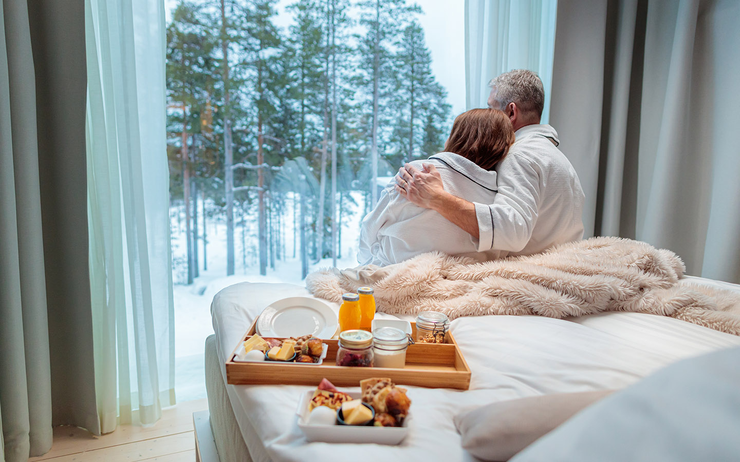 Couple enjoying slow morning and breakfast in bed at the Arctic TreeHouse Hotel.