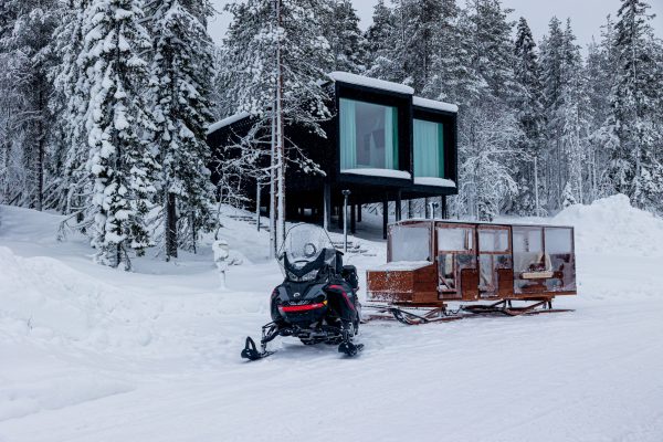 Snowmobile and sledge next to Arctic TreeHouse Hotel suite.