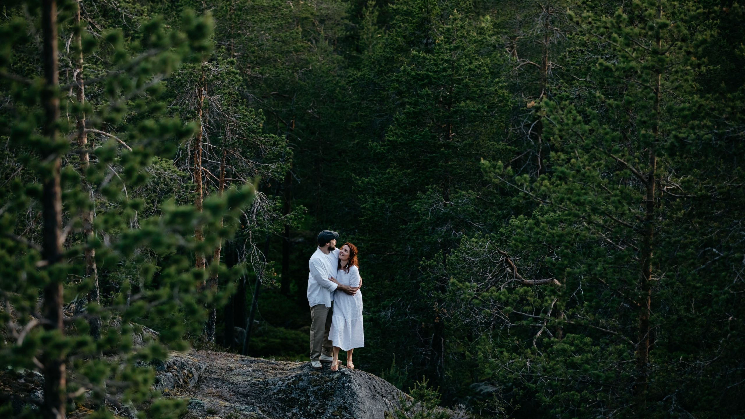 Couple in love under the midnight sun in northern forest at Arctic TreeHouse Hotel