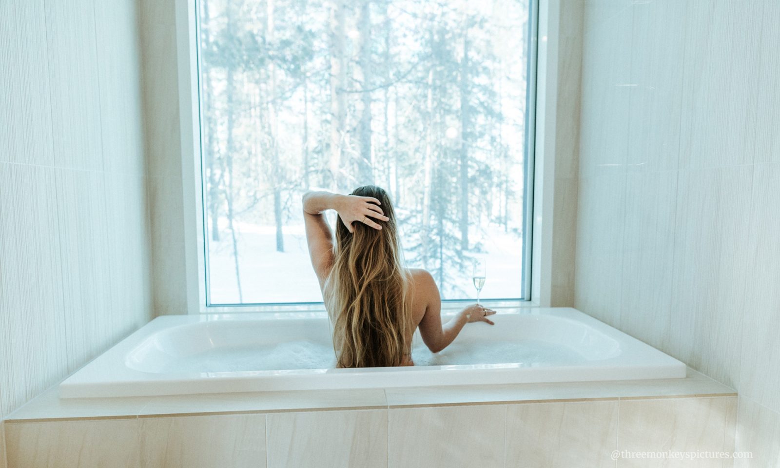 Woman enjoying bath in Arctic Scene Executive Suite at Arctic TreeHouse Hotel.