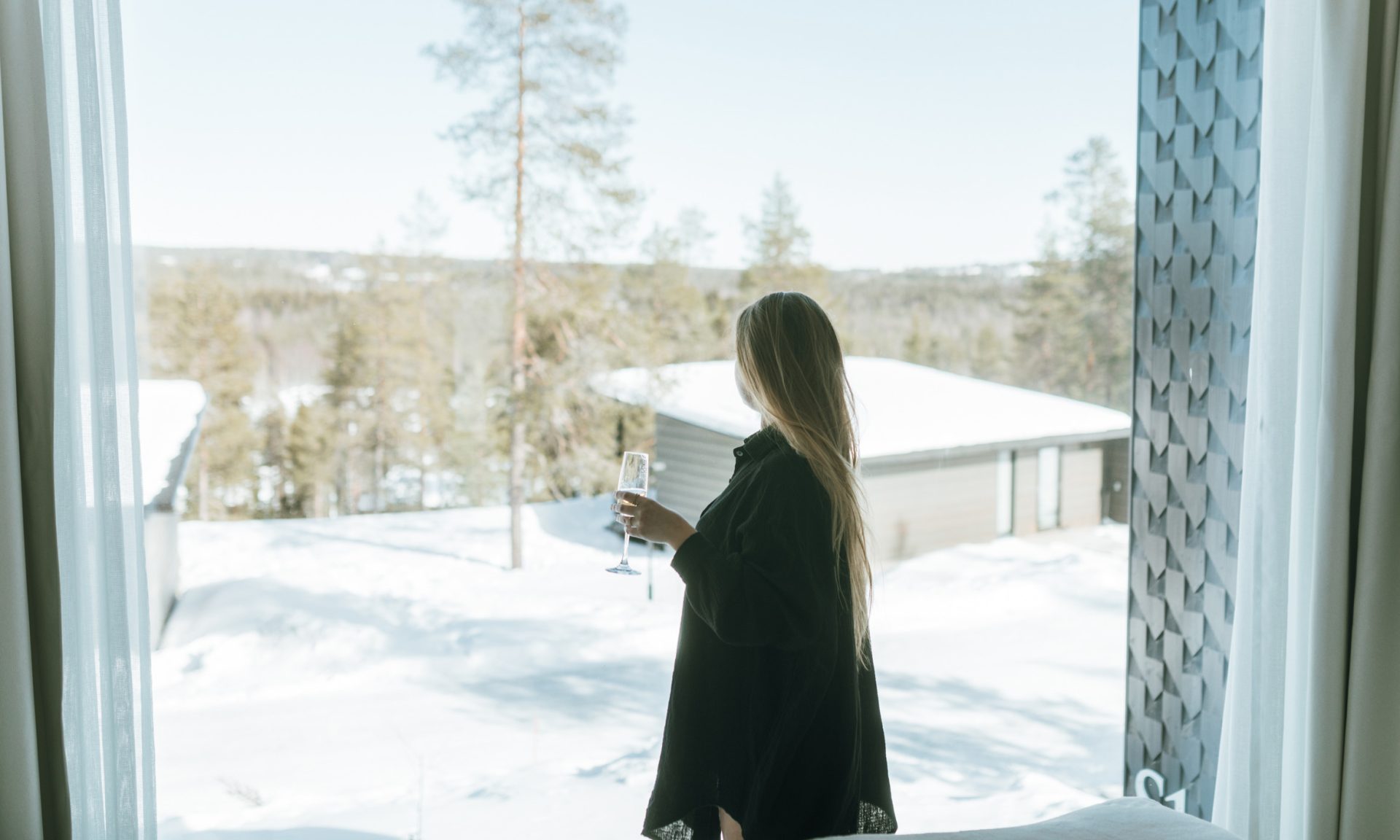 A woman enjoying a sunny spring time in Lapland, Arctic TreeHouse Hotel suite.