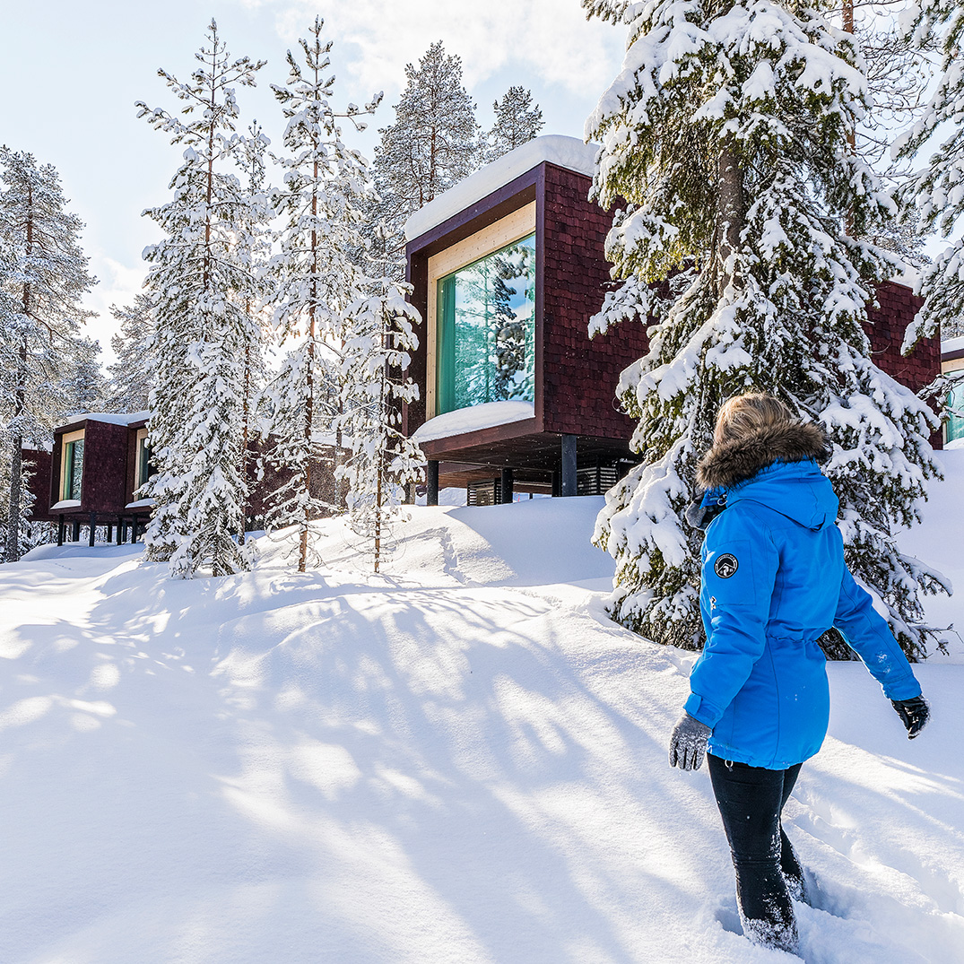 A woman walking in the snow at Arctic TreeHouse Hotel
