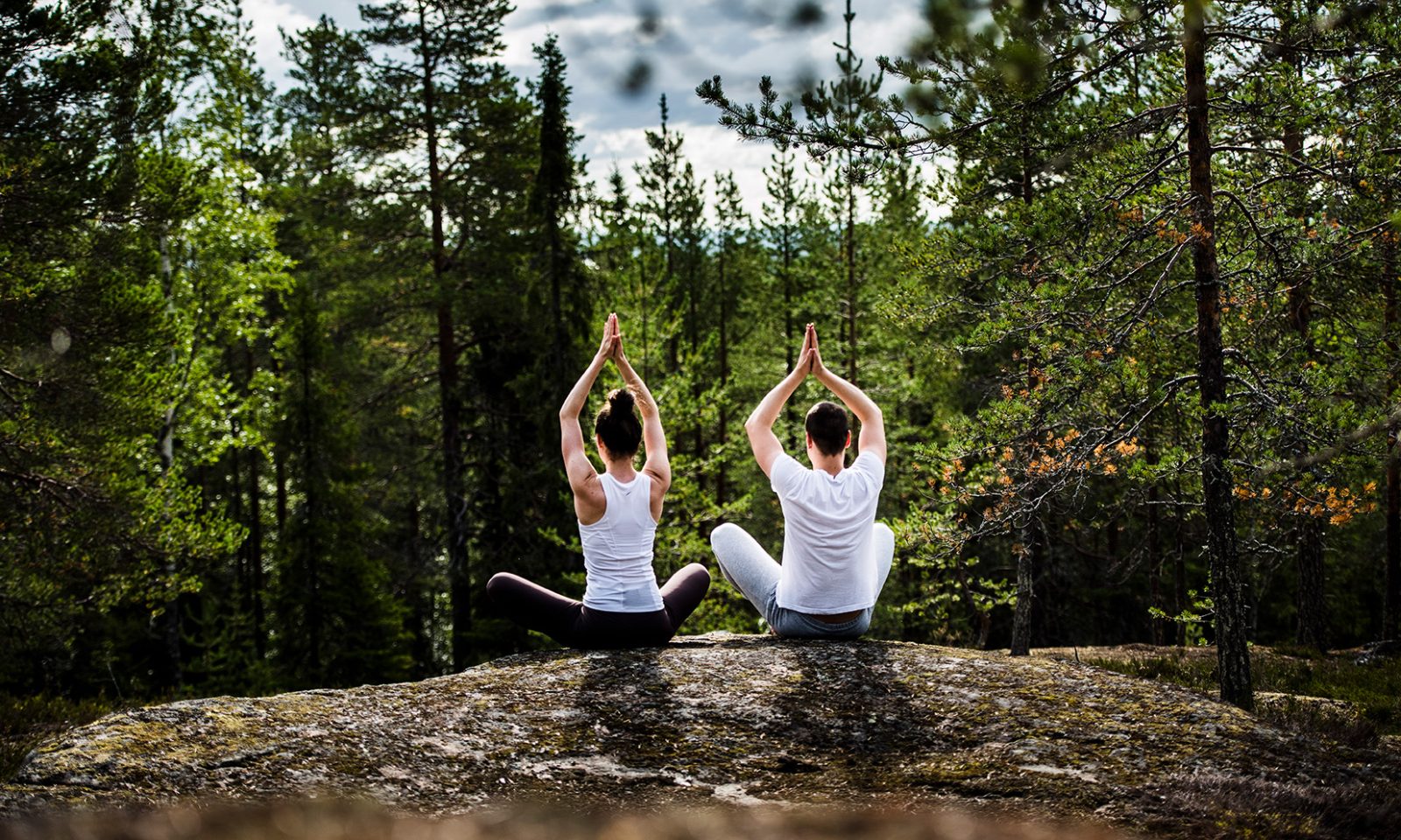 A man and a woman practising mindfullness in a northern forest.