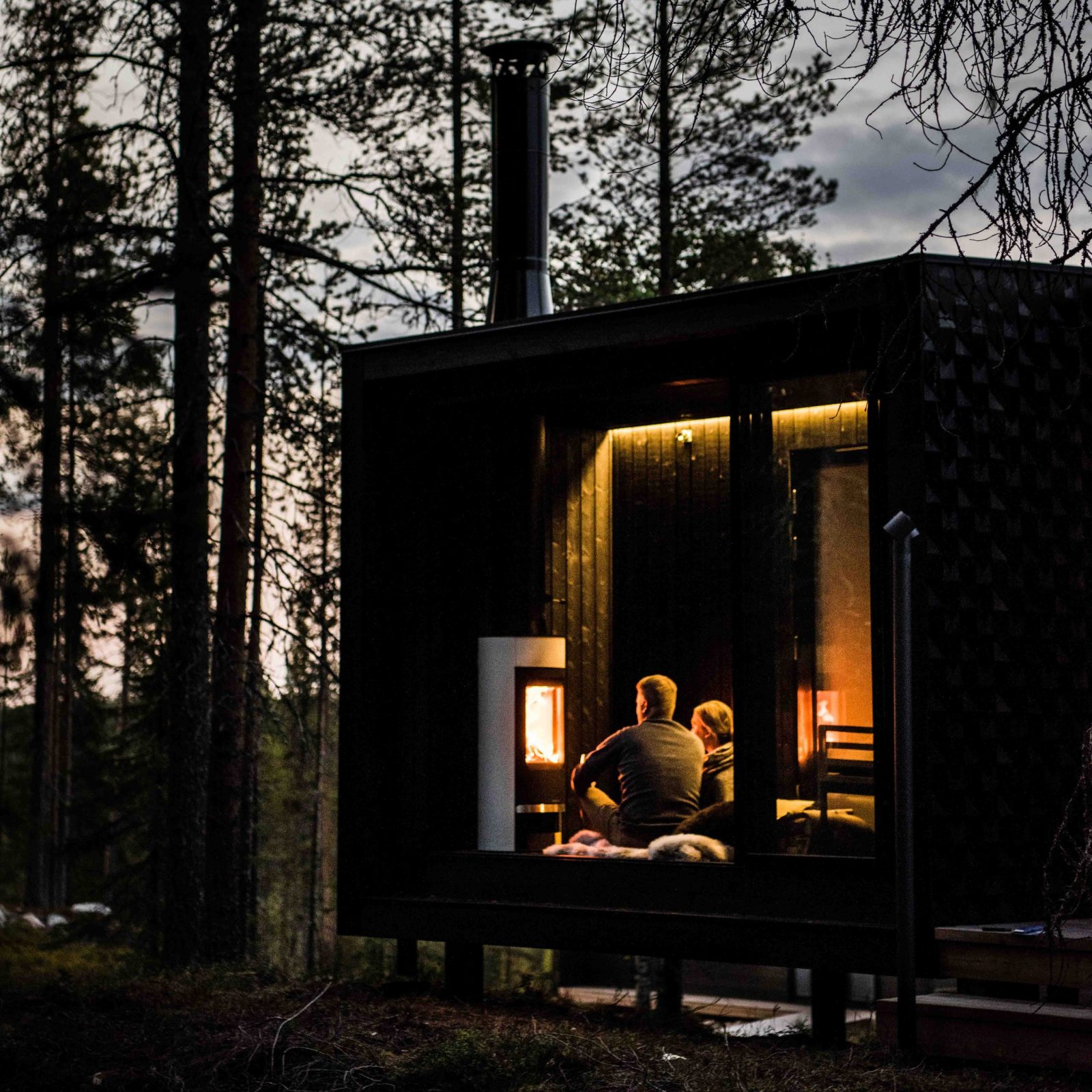 A couple is enjoying autumn night by the fire at the Arctic TreeHouse Hotel
