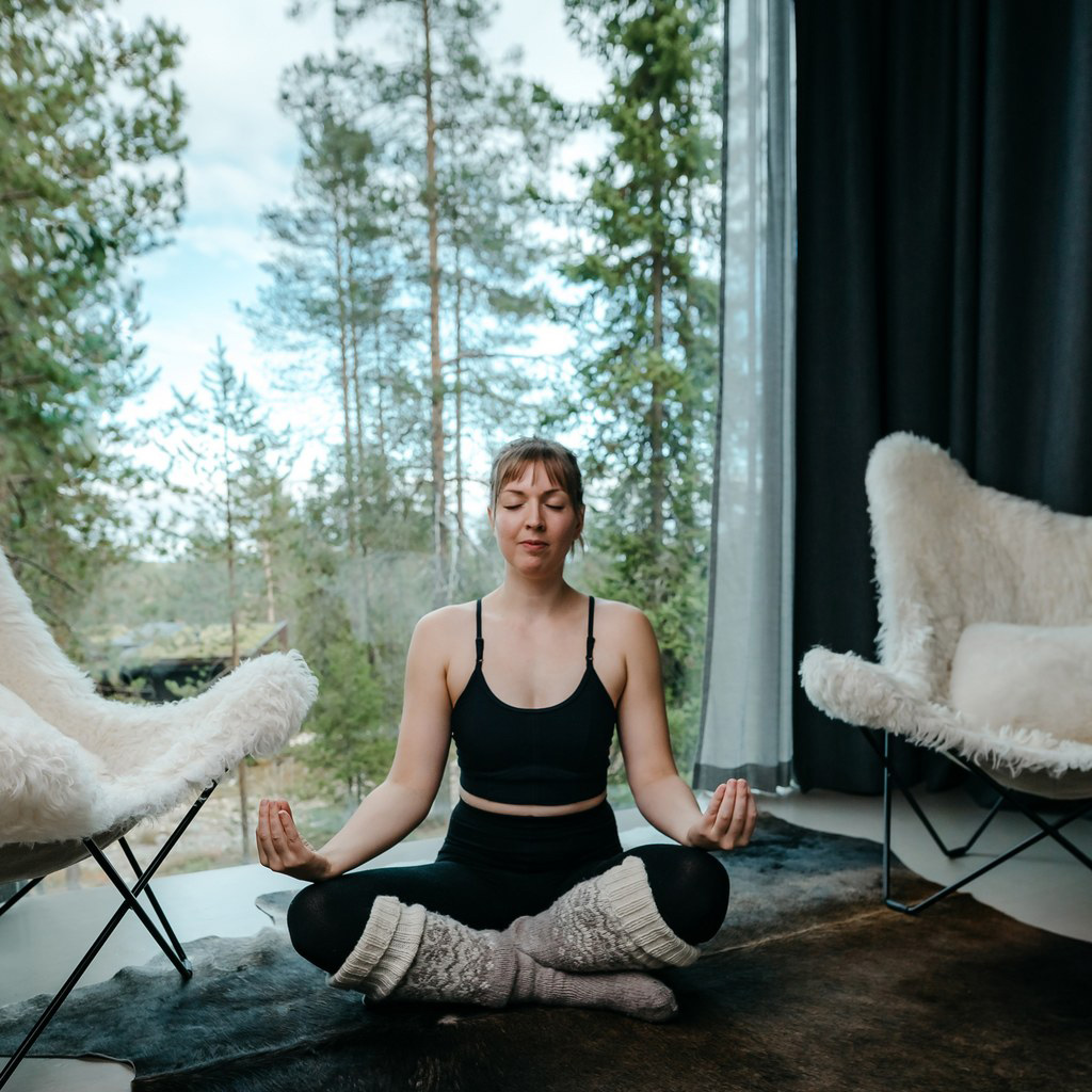 A woman in relaxing and meditating in Arctic TreeHouse Suite.