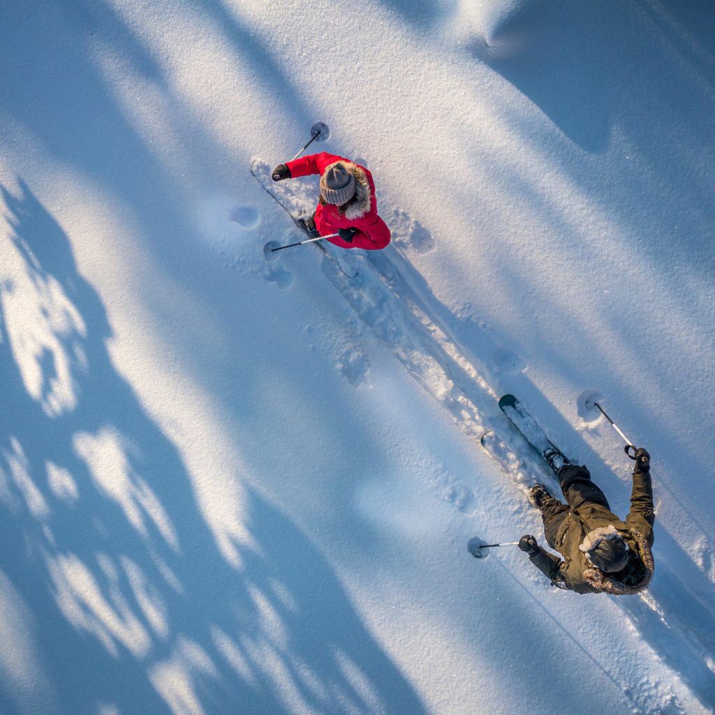 Nainen ja mies lumikenkäilemässä Lapin luonnossa.