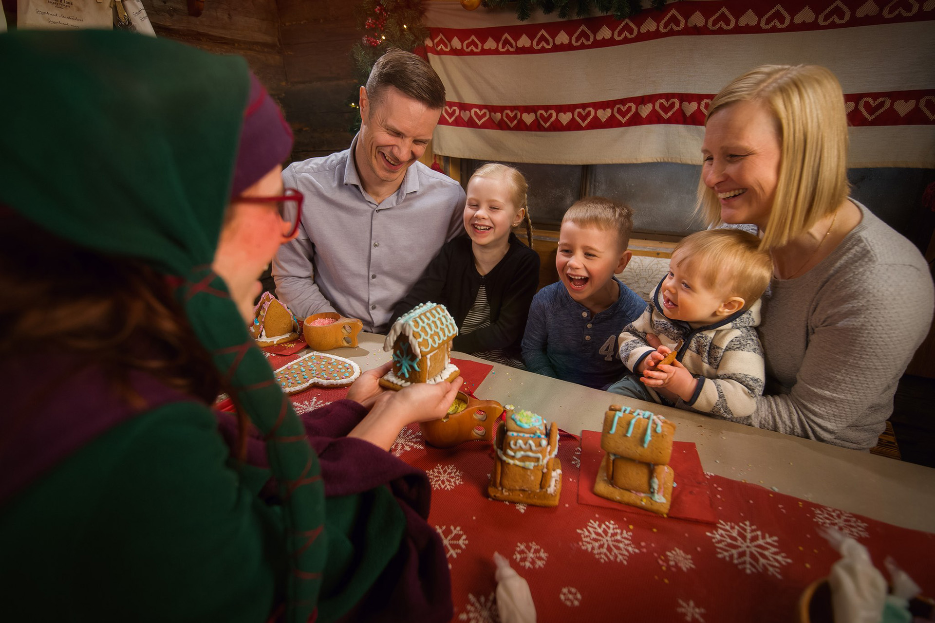 Family and Elf enjoying decorating gingerbread houses in the Private Gingerbread Masterclass with Santa Claus program, Rovaniemi.