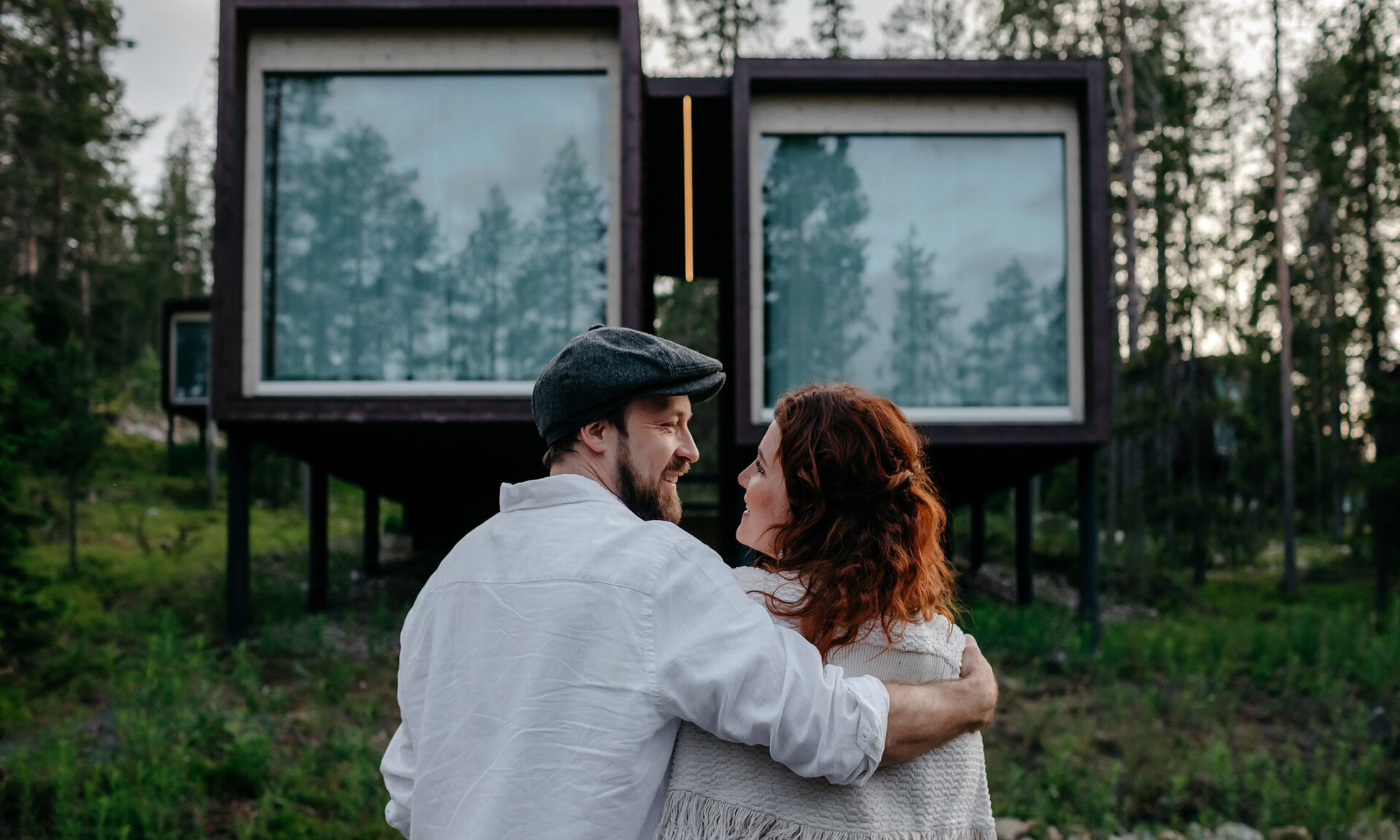 Couple in front of the Arctic TreeHouse Suites in summer. | Rovaniemi, Finland.