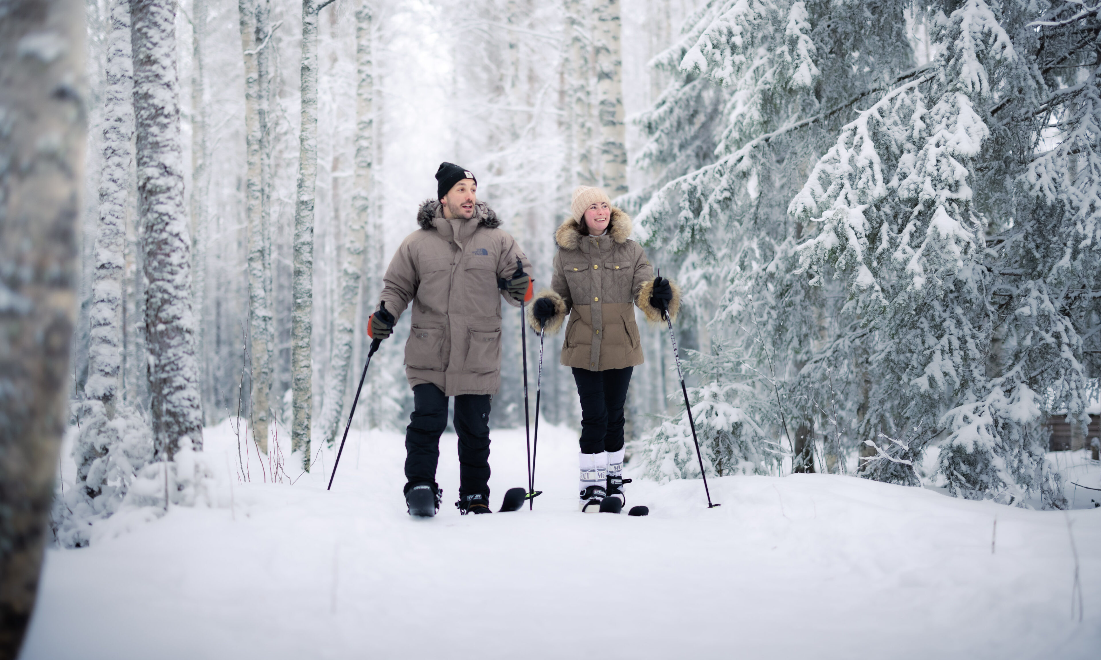 Couple back country skiing in wintry forest of Rovaniemi, Lapland, Finland.